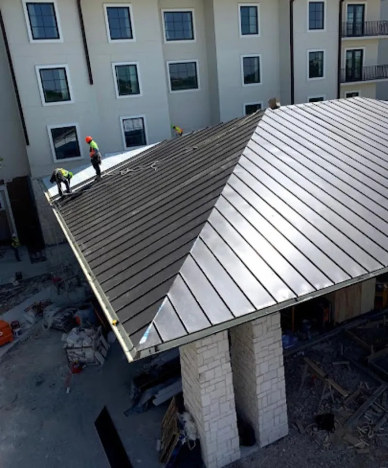 Crew installing standing seam metal roof panels on a commercial project in Graham